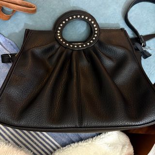 Bolso negro con asa redonda y tachuelas