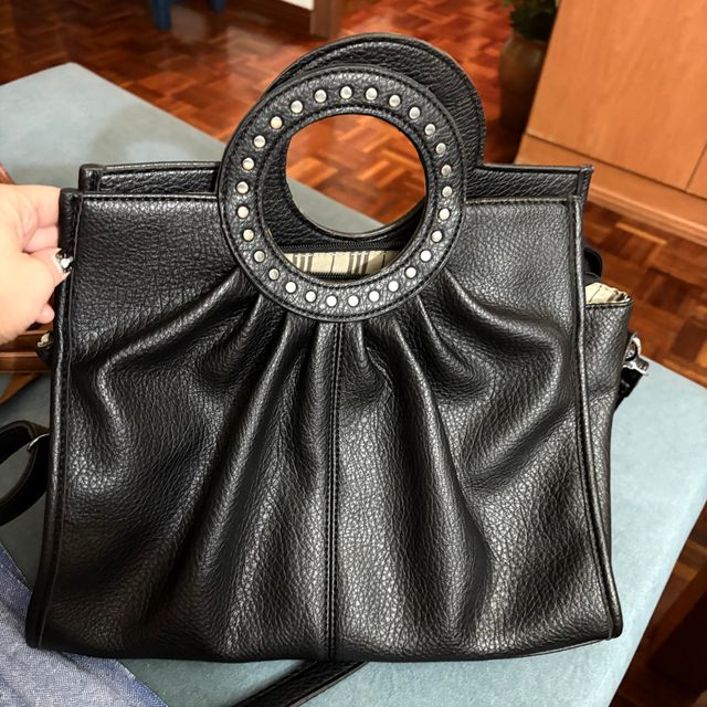 Bolso negro con asa redonda y tachuelas