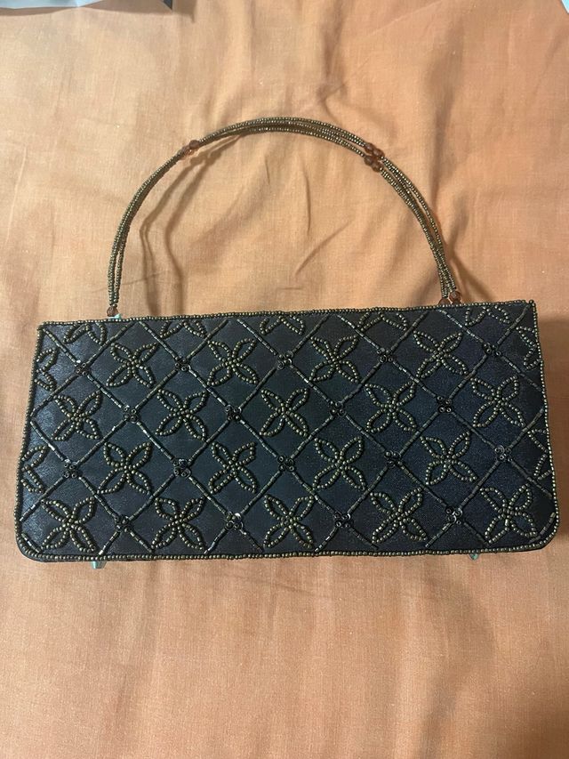Bolso de mano negro con detalles dorados