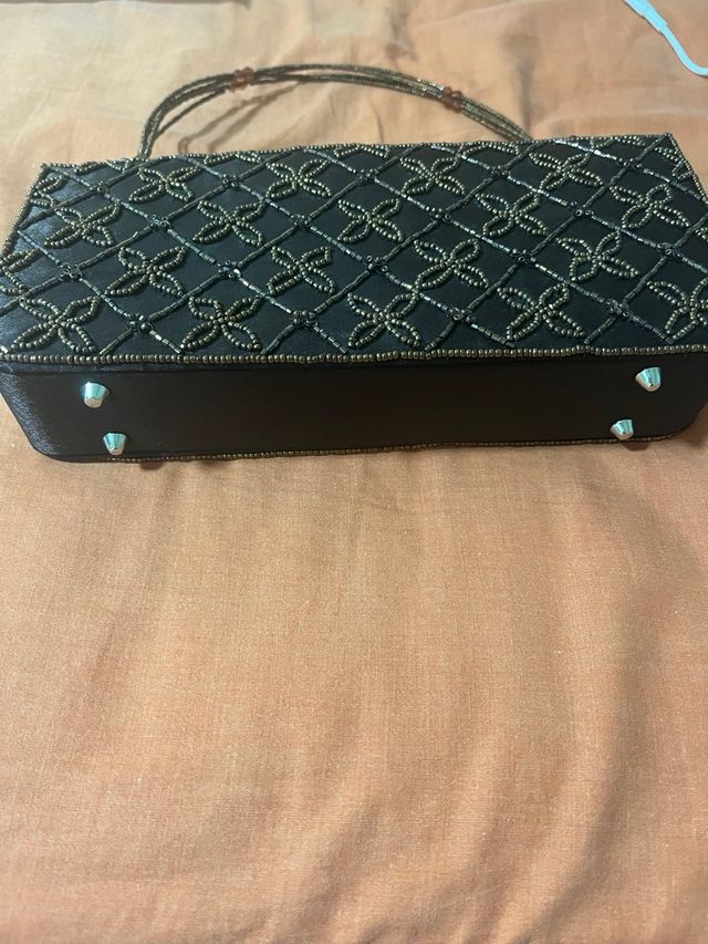 Bolso de mano negro con detalles dorados