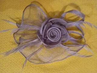 Tocado gris plata con flor y plumas.