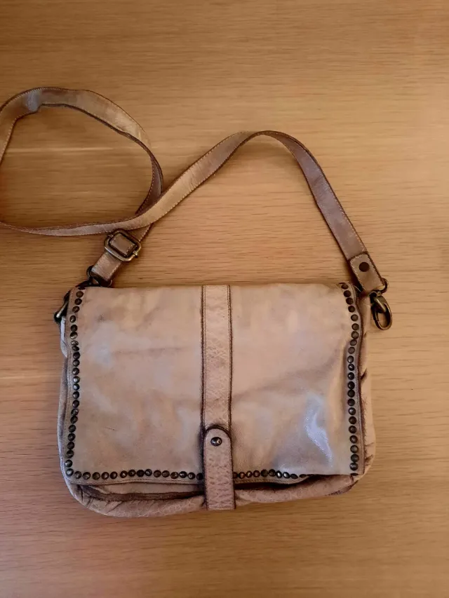 Bolso bandolera piel beige tachuelas.