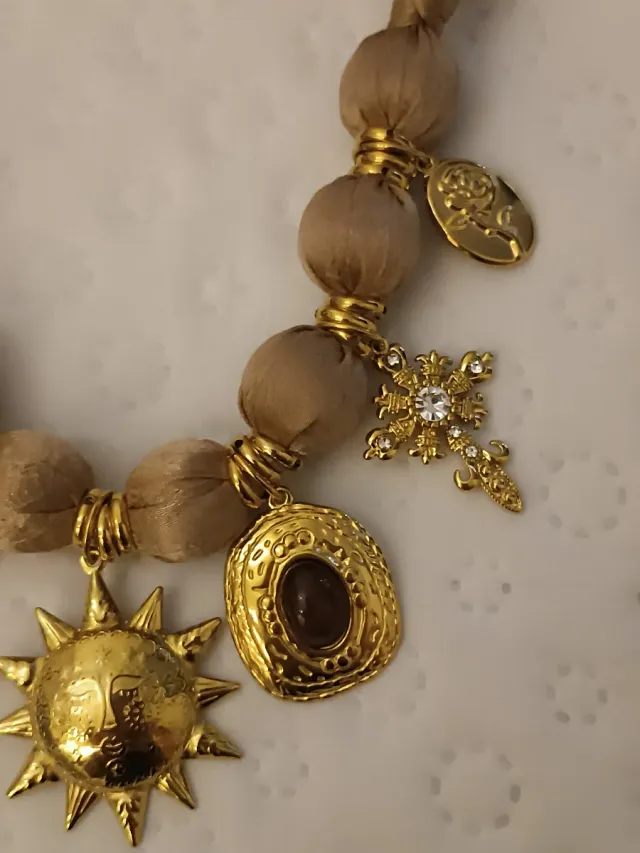 Collar tela beige con cierre y dijes dorados