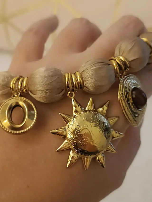 Collar tela beige con cierre y dijes dorados