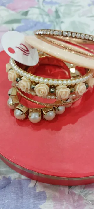 Set braccialetti dorati con perle e rose rosse