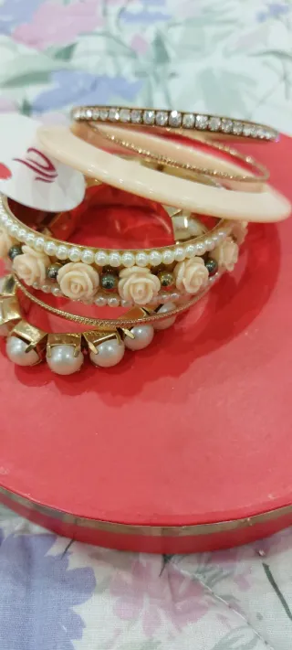 Set braccialetti dorati con perle e rose rosse