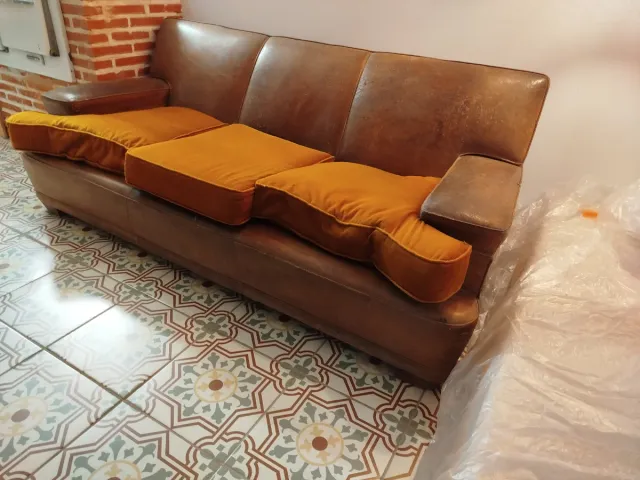 Sofá de cuero vintage marrón con cojines naranjas