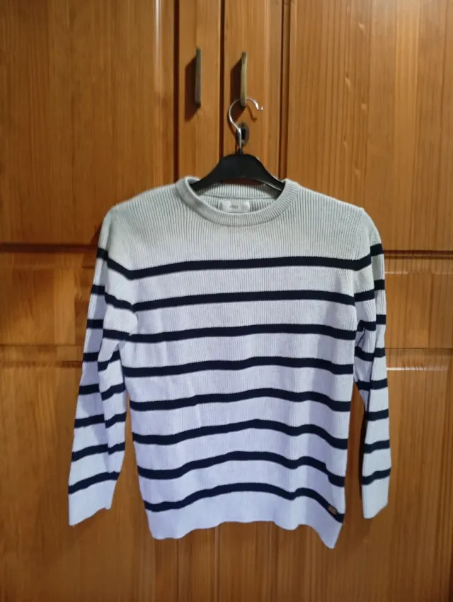 Jersey gris con rayas negras.