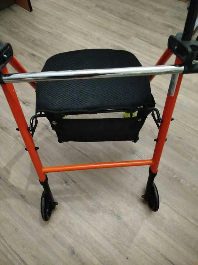 Andador geriátrico naranja con asiento y ruedas