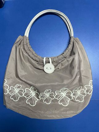 Bolso color caqui con asas de piel blancas.