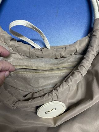 Bolso color caqui con asas de piel blancas.