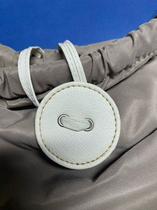 Bolso color caqui con asas de piel blancas.