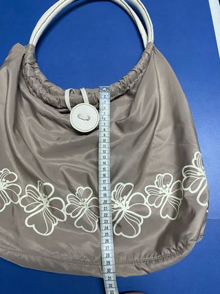 Bolso color caqui con asas de piel blancas.