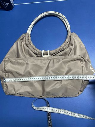 Bolso color caqui con asas de piel blancas.