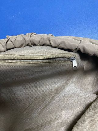 Bolso color caqui con asas de piel blancas.