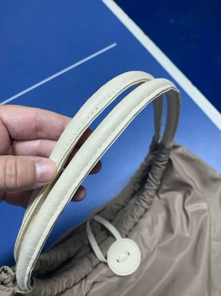 Bolso color caqui con asas de piel blancas.