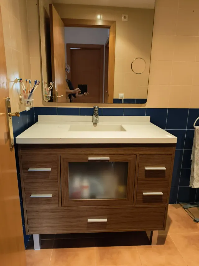 Mueble de baño madera y cristal con pila y grifo.