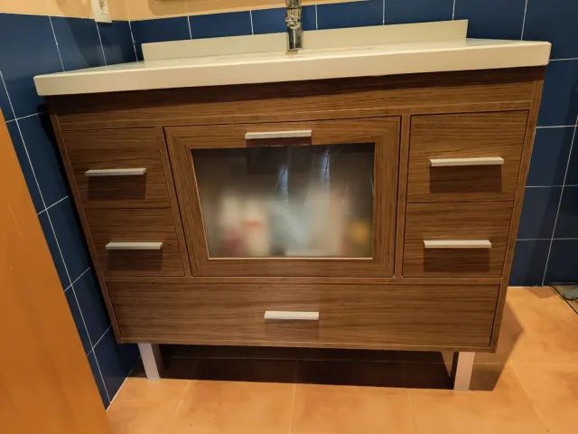 Mueble de baño madera y cristal con pila y grifo.
