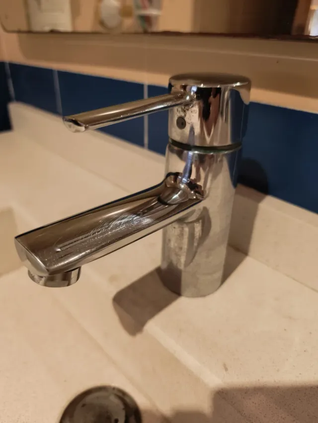 Mueble de baño madera y cristal con pila y grifo.