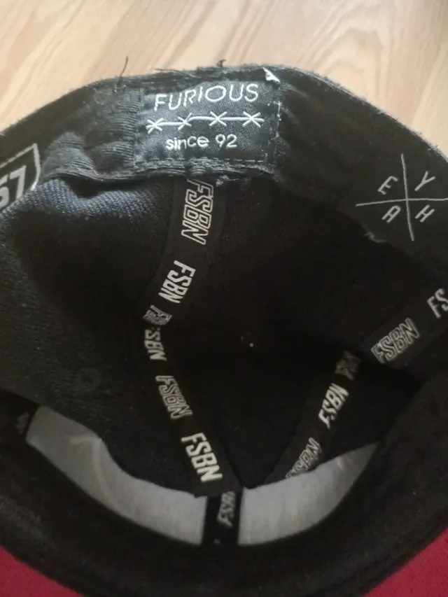 Gorra negra y roja con diseño de cara sonriente