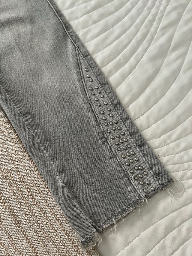 Pantalón gris con tachuelas.