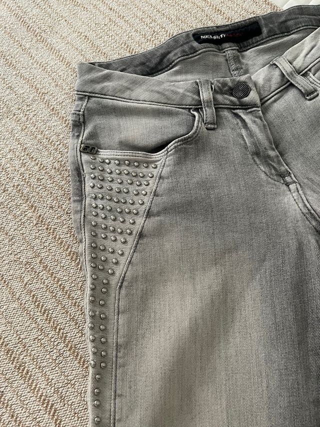 Pantalón gris con tachuelas.