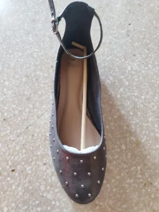 Zapatos planos plateados con tachuelas.