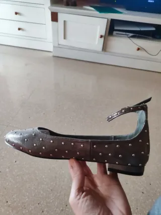 Zapatos planos plateados con tachuelas.