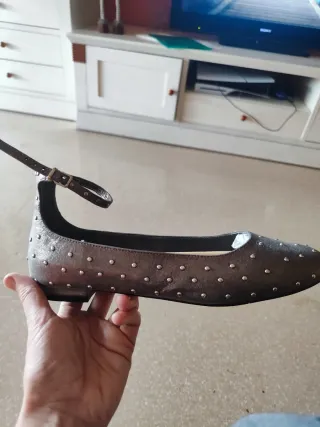 Zapatos planos plateados con tachuelas.