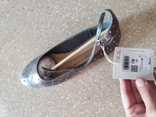 Zapatos planos plateados con tachuelas.