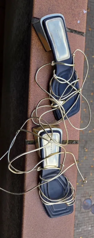 Sandalias doradas con tiras negras