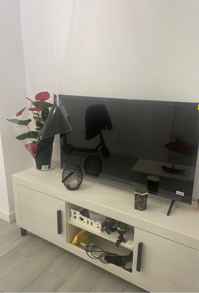 Mueble TV beige con puertas y tiradores negros.