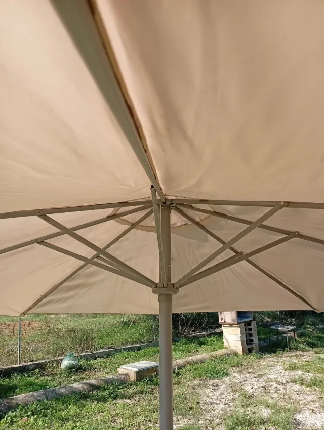 Sombrilla beige con pie de hormigón