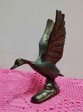 Figura de bronce pato en pleno vuelo.