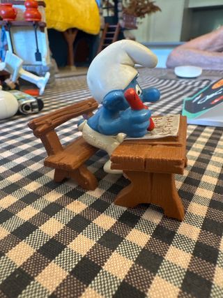 Pitufo estudiante con pupitre y lápiz