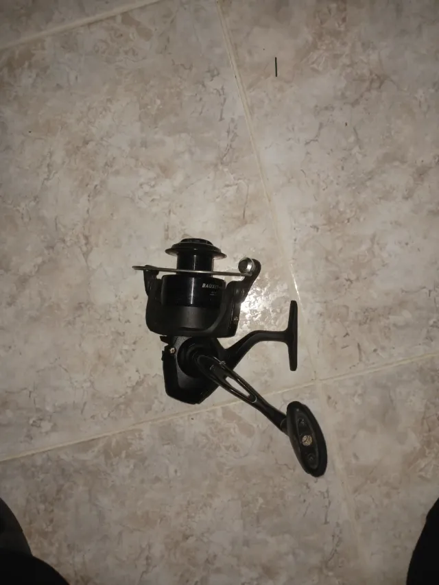 Carrete de pesca negro y caña