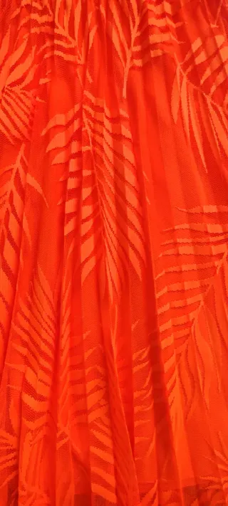 Falda naranja plisada con estampado de hojas.