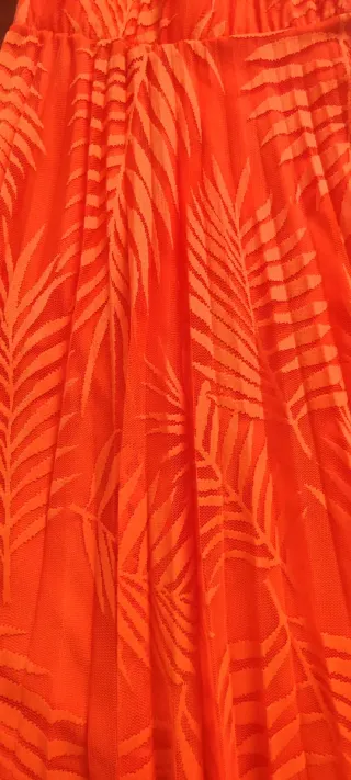 Falda naranja plisada con estampado de hojas.