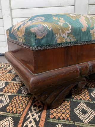 Puf baúl tapizado y con patas de madera.