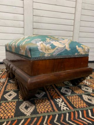 Puf baúl tapizado y con patas de madera.