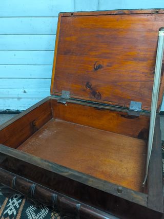 Puf baúl tapizado y con patas de madera.