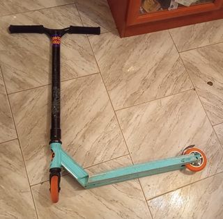 Patín de trucos azul con ruedas naranjas