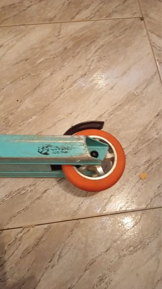 Patín de trucos azul con ruedas naranjas