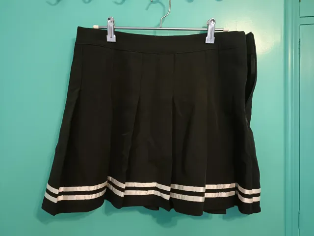 Falda corta negra plisada con rayas.