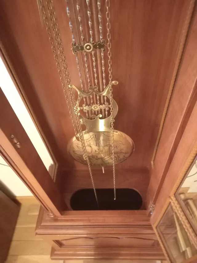 Reloj de pie de madera con desperfectos.