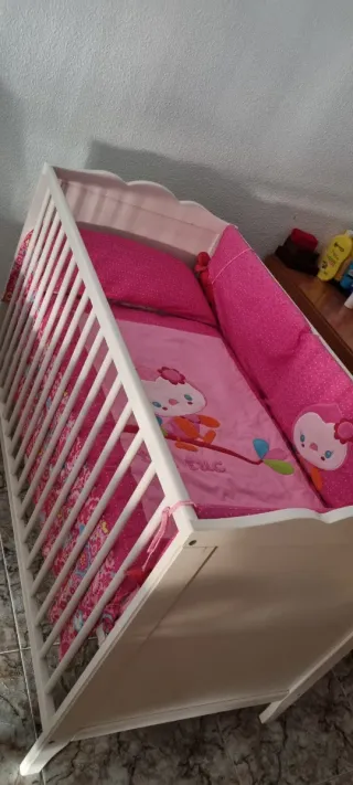 Cuna blanca con ropa de cama rosa