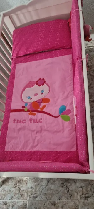 Cuna blanca con ropa de cama rosa
