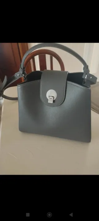 Bolso gris con cierre metálico.