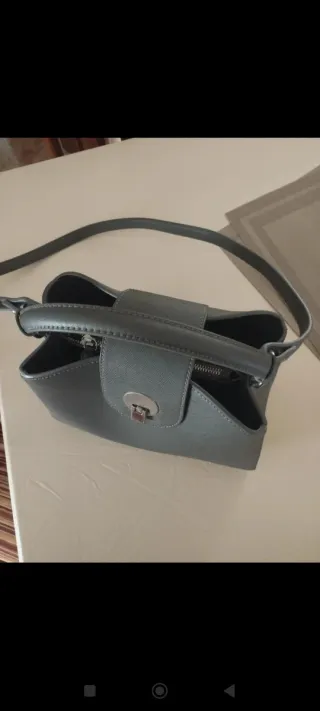 Bolso gris con cierre metálico.