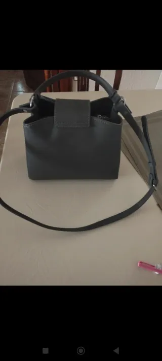 Bolso gris con cierre metálico.